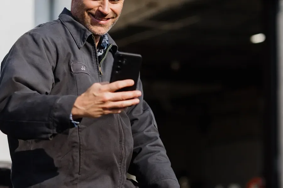Caminhoneiro sorrindo enquanto usa o celular